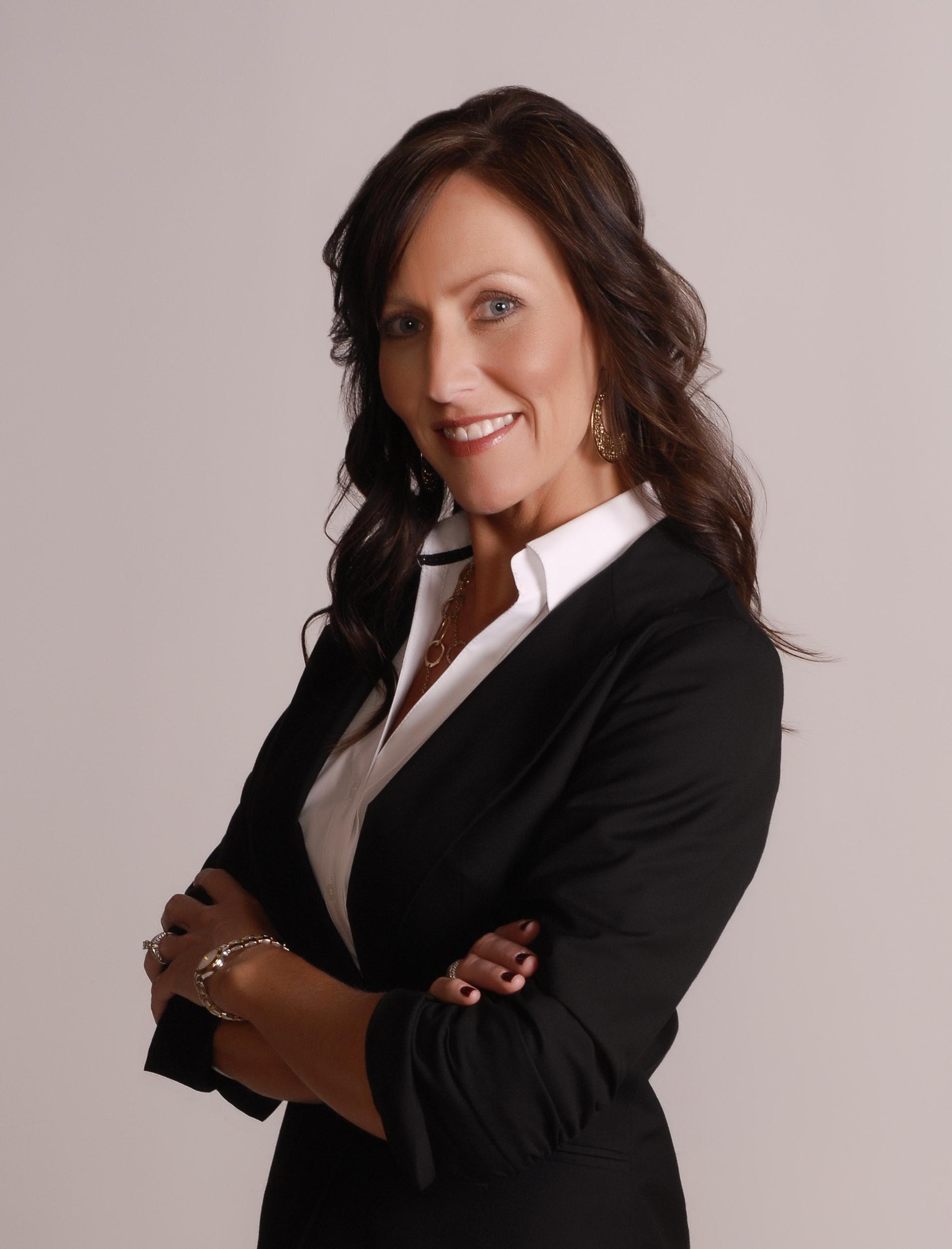 A woman in black jacket standing with her arms crossed.