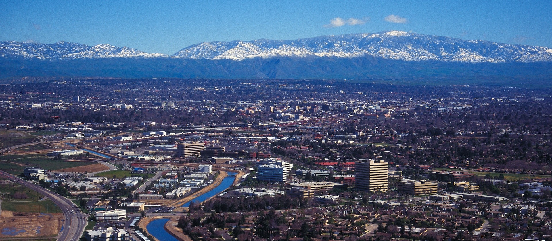 A view of the city from above with snow capped mountains in the background.